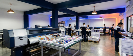 A professional DTF printing facility with a high-capacity printer and organized stacks of vibrant film transfers ready for production.